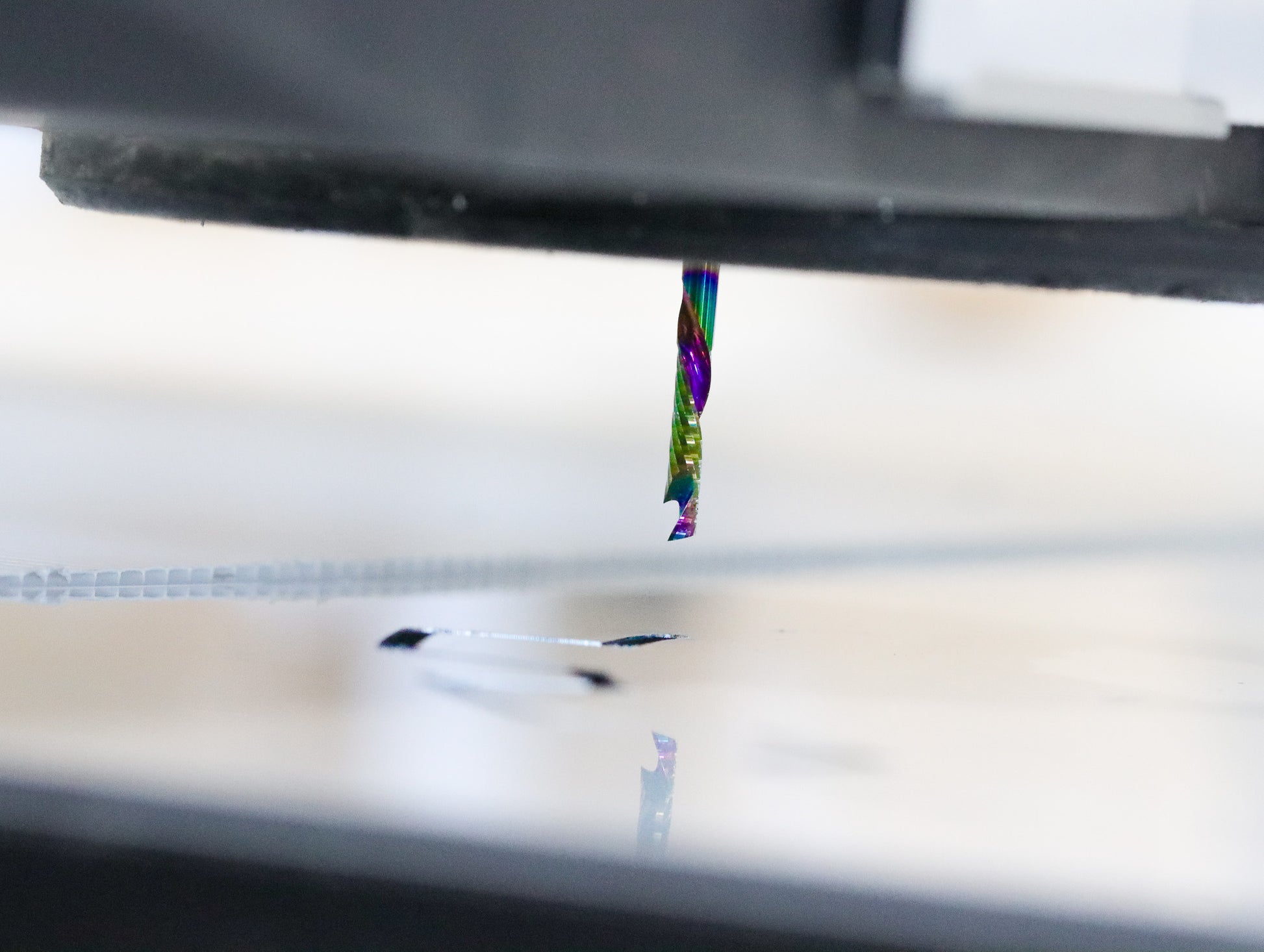 Atlas Tools Compression Spiral 1F 3.175x12 (DLC Coating) ULTRACLEAN for ACM and ACP hovering above material engaged in action shot closeup