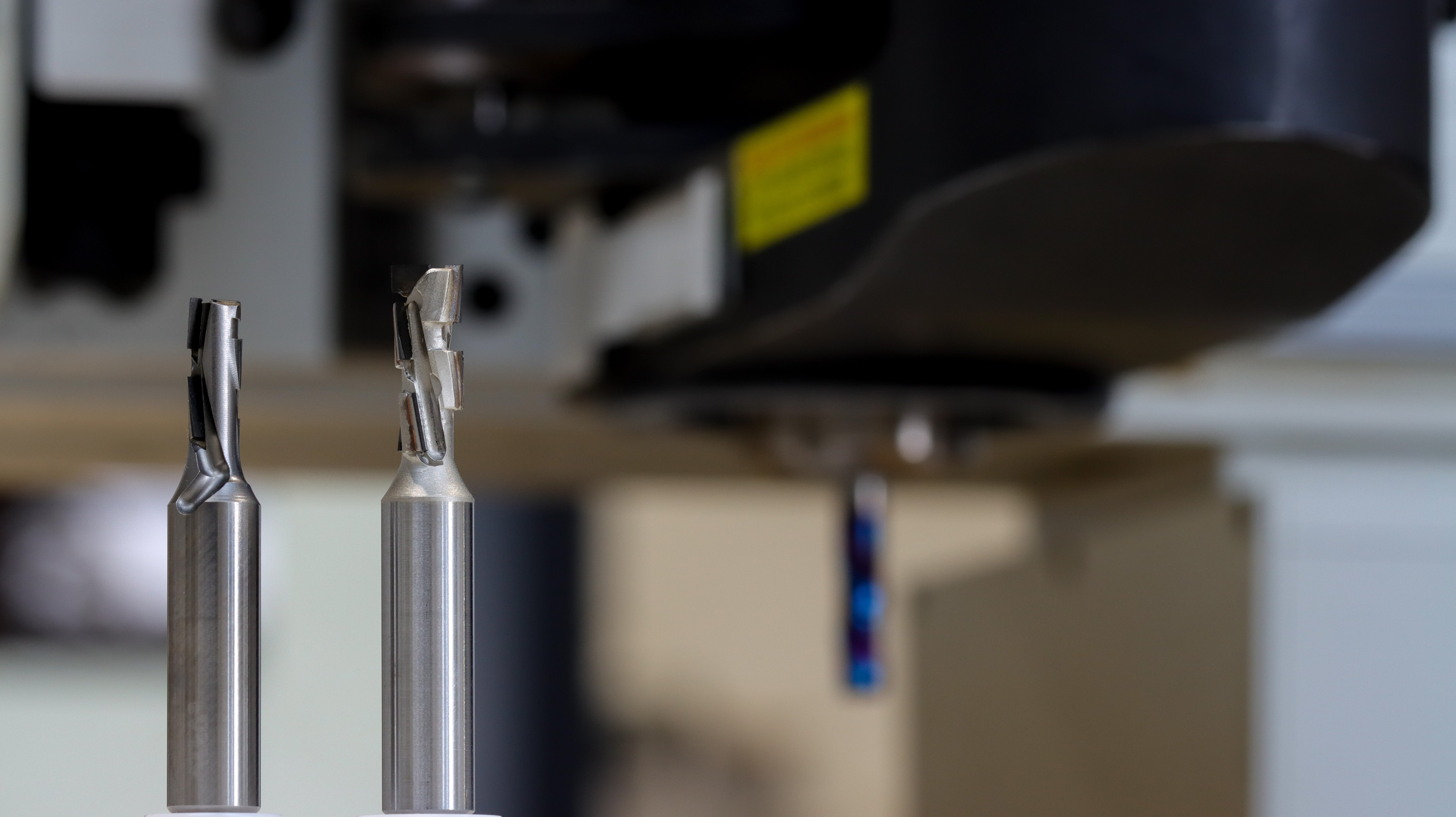 Atlas Tools Image of Two Diamond Compression Bits side shot and Blurred CNC Router in Background